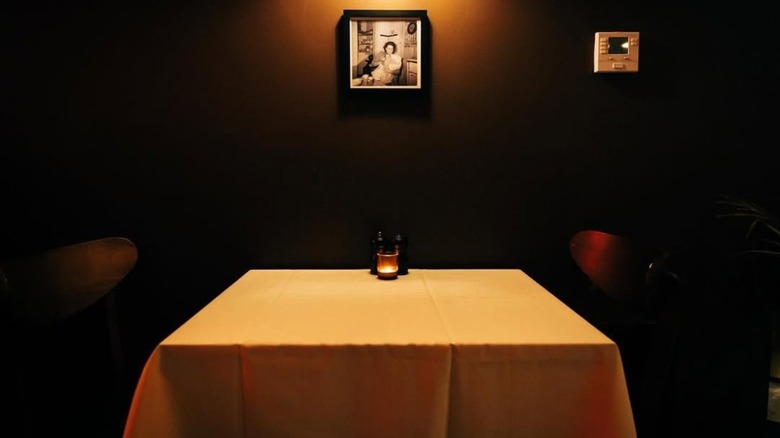 A dimly lit table with a beige cloth and a framed vintage photo at Pizz'amici