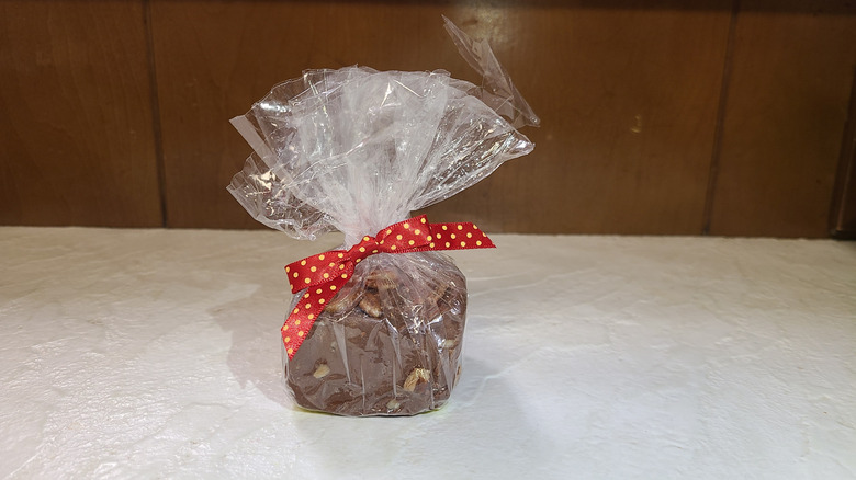 Individually wrapped square of fudge with red bow in front of wood background