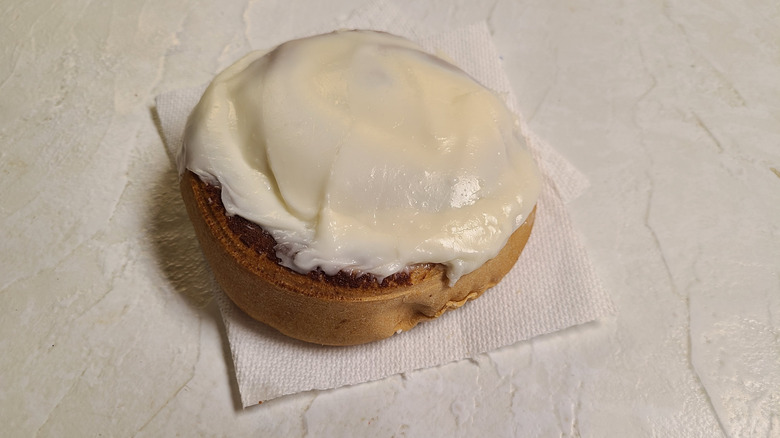 Buc-ee's cinnamon roll with cream cheese icing on paper towel on a white table