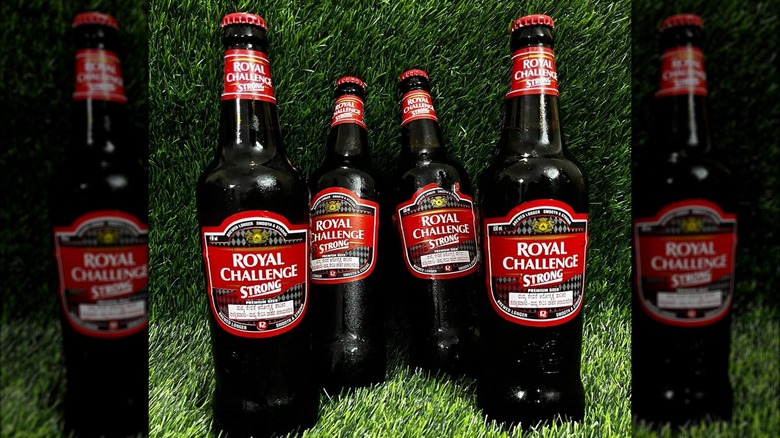Four bottles of Royal Challenge beer resting on fake grass