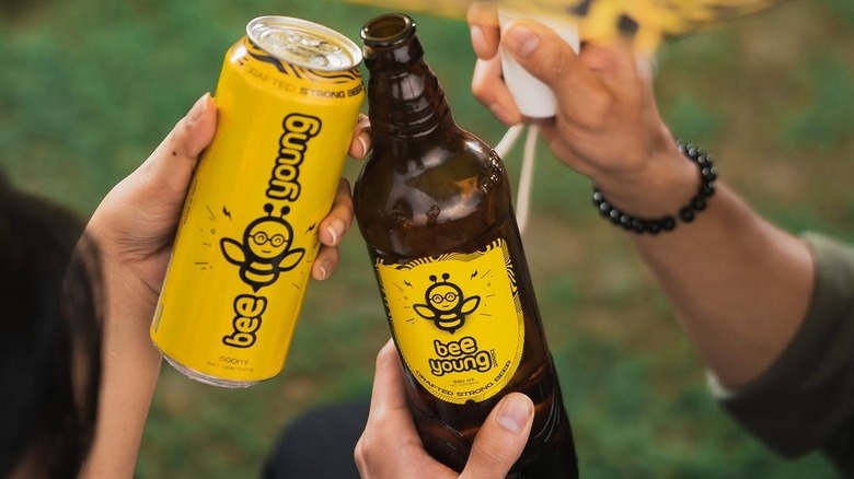 A bottle and a can of Bee Young being held up