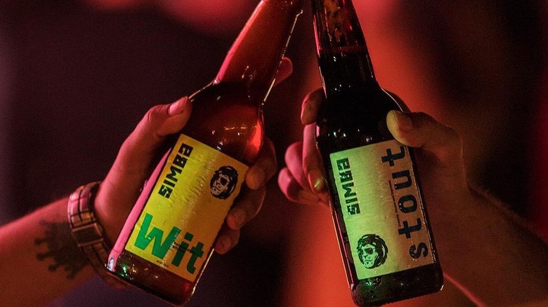 Two different bottles of Simba beer being clinked together