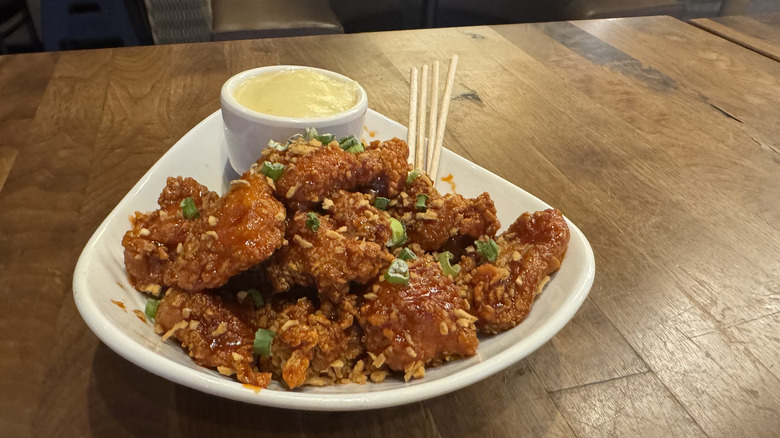 A small plate is full of boneless wings with garlic and a dipping sauce.