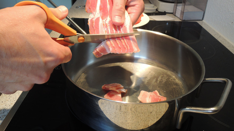 Shears slicing strips of bacon