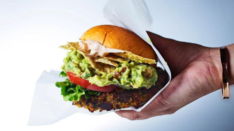 Veggie guacamole burger in hand