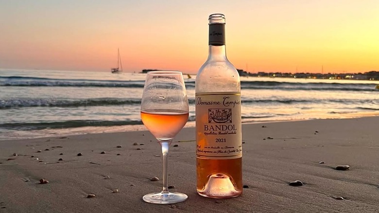 A bottle and glass of Domaine Tempier Bandol rosé on the beach at sunset