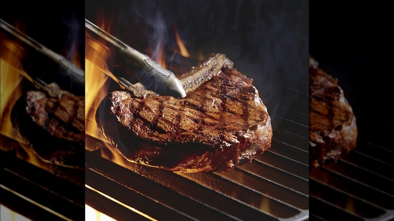 Grilled steak with tongs