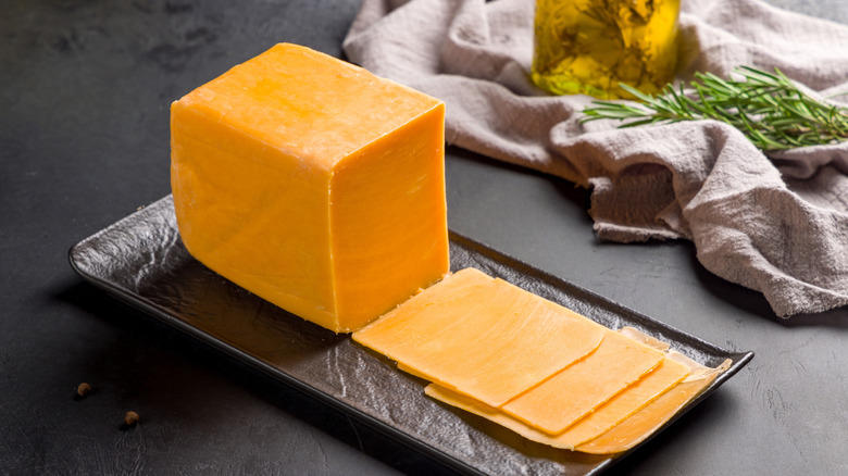 Sliced yellow cheddar on black serving tray