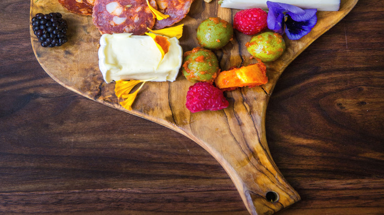 Edible flowers on charcuterie board with seeds and cheese