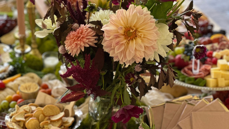 Charcuterie boards laid out on grazing table with bouquet of flowers in the center