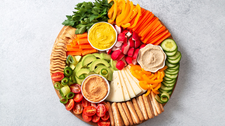 Colorful vegetable board with dipping sauces and vegan cheese