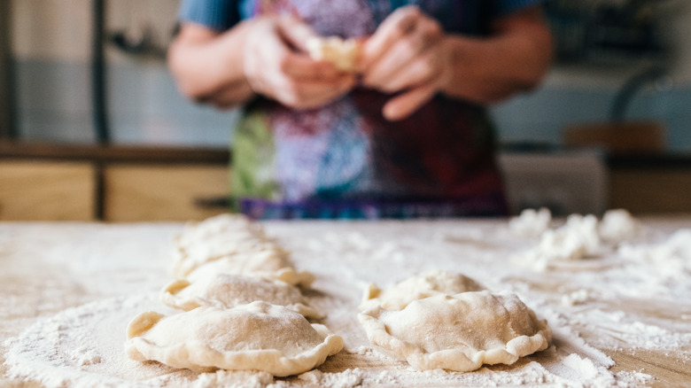 Person stuffing and crimping pierogis