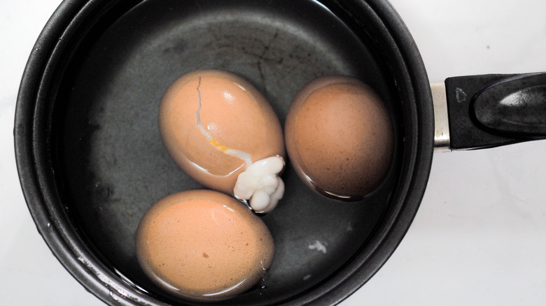 Cracked eggs in a pot of water