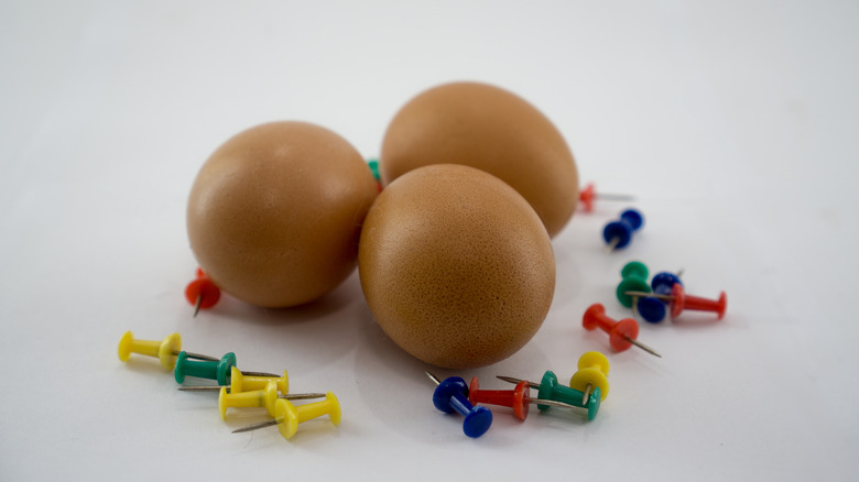 Eggs surrounded by thumbtacks