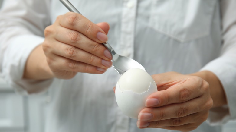 Removing an egg shell with a spoon