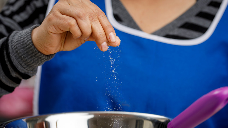 Woman sprinkling salt into bowl