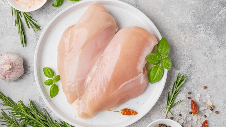 Raw chicken breasts on plate