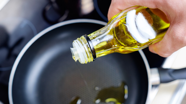 Person adding oil to pan