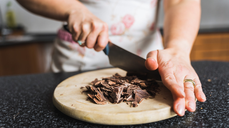 Person chopping chocolate on wood