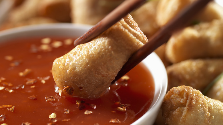 Egg roll dipped in chili sauce. 