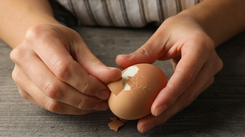 Hands peeling hard boiled egg