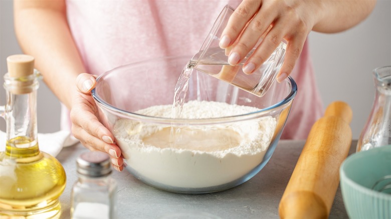 Woman making dough with water, flour, and oil