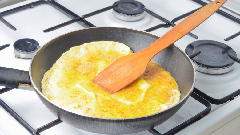 Eggs cooking with wooden spatula