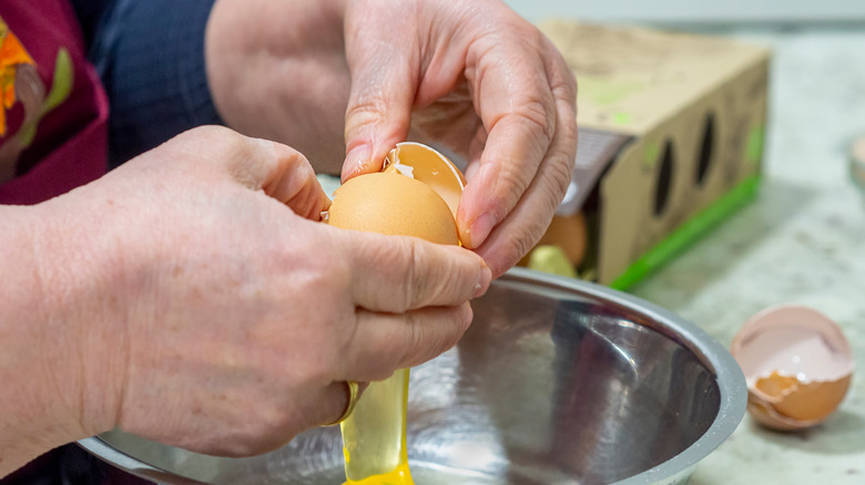 Person cracking eggs over bowl