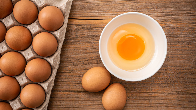 Egg in bowl beside a dozen eggs