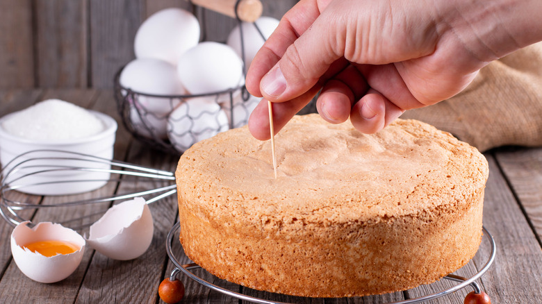 Person poking cake with toothpick