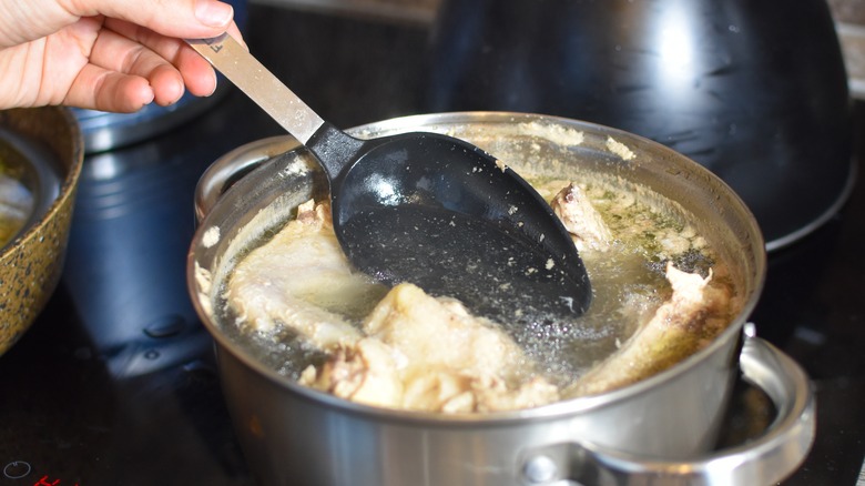 Person skimming broth with spoon