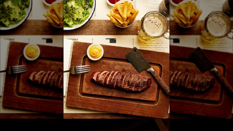 steak on board with cleaver and mustard