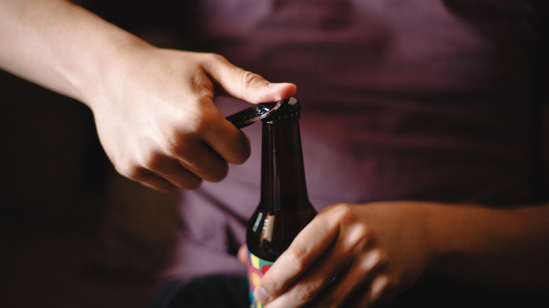 Close up of a hand opening a craft beer bottle