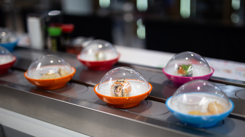 A conveyor belt with color-coded plates at a sushi restaurant