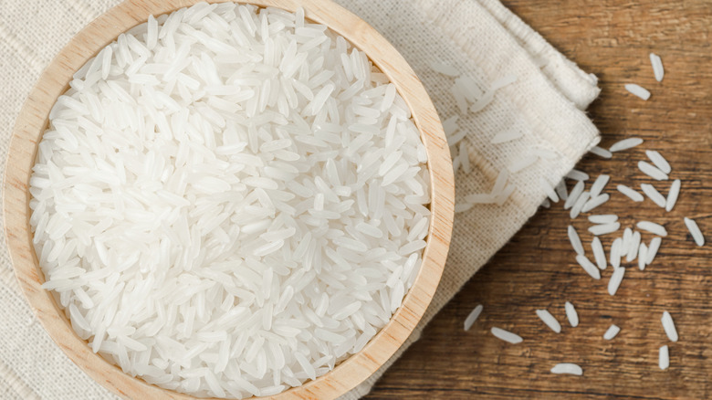 Wooden bowl filled with uncooked white rice grains