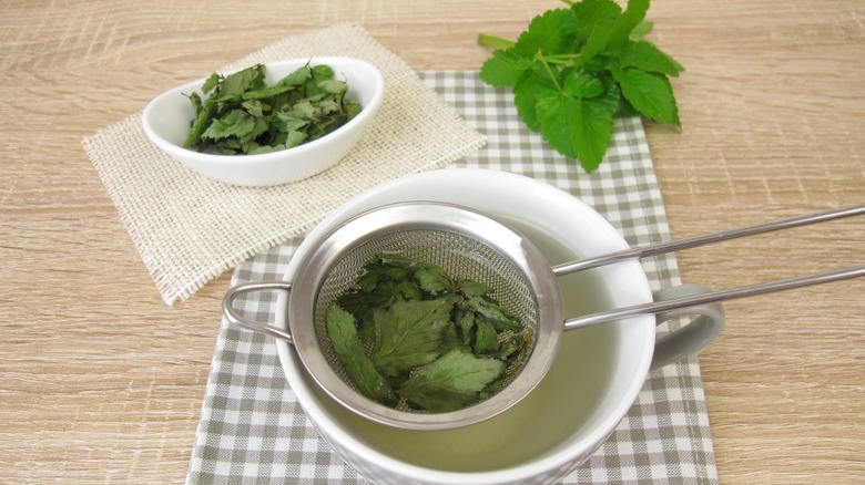 straining herbal tea into cup