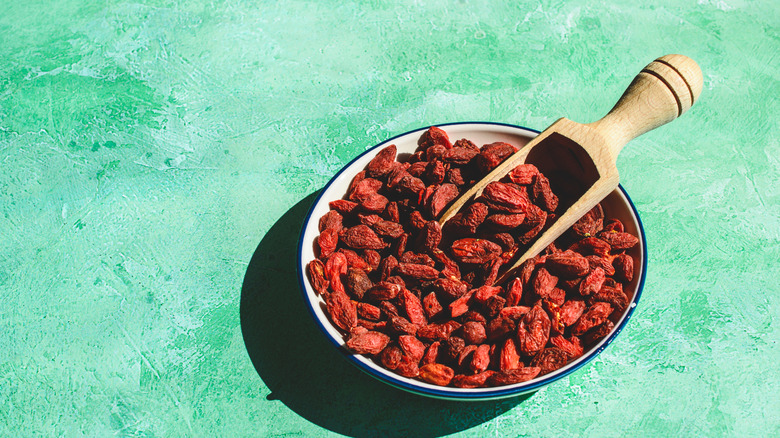 Dried goji berries in bowl on aqua background