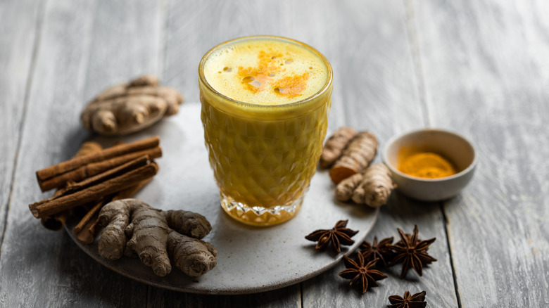 Hot cup of badam doodh with spices on grey plate