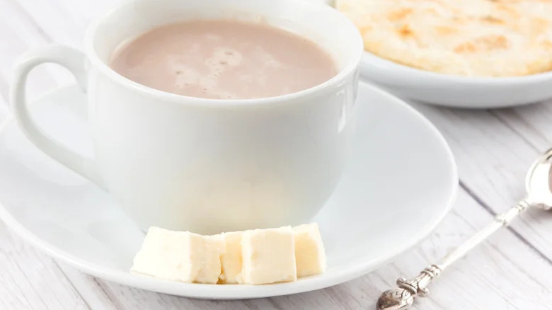 Cup of hot chocolate with chunks of cheese on grey table