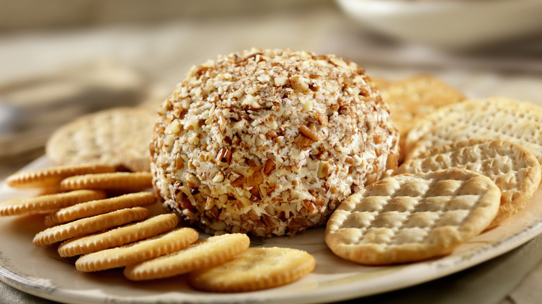 Close-up of cheese ball covered i ntoasted nuts with crackers on a plate