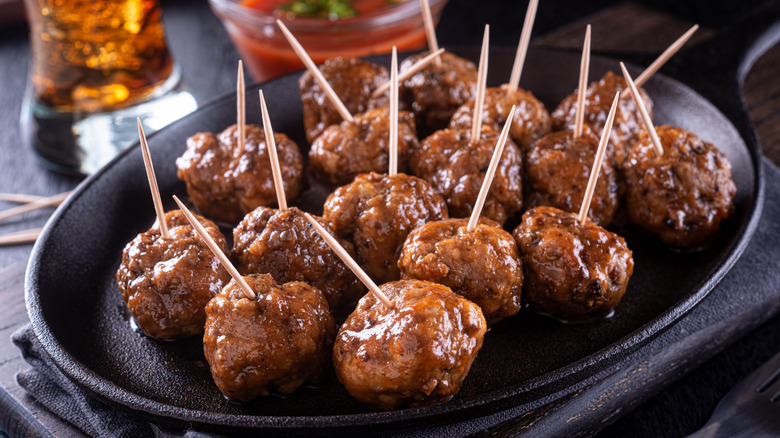 Black plate of tiny meatballs with a toothpick in each one