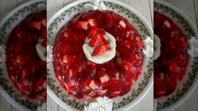 Red molded Jell-O stuffed with fruit and topped with cream
