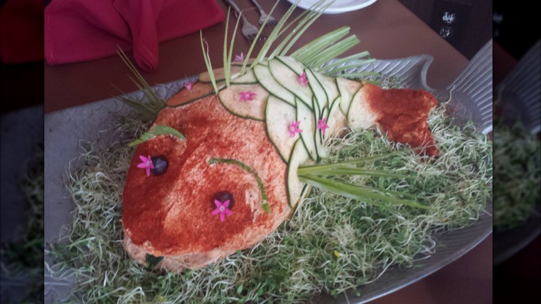 Salmon mousse molded into a fish shape with spices, veggies and flowers