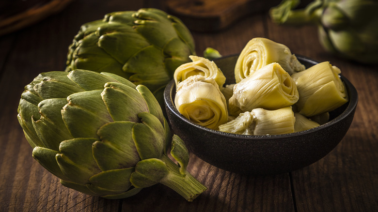 Artichoke hearts in bowl with artichokes