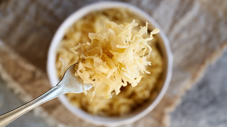 Fork lifting sauerkraut from bowl