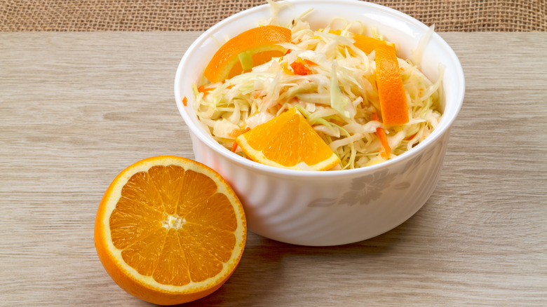 bowl of sauerkraut with halved orange next to it