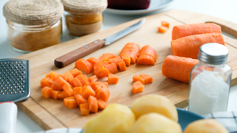 Root vegetables on wooden cutting board with knife