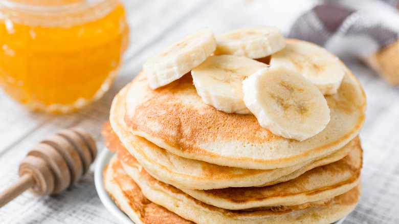 Banana pancakes on plate with honey in background