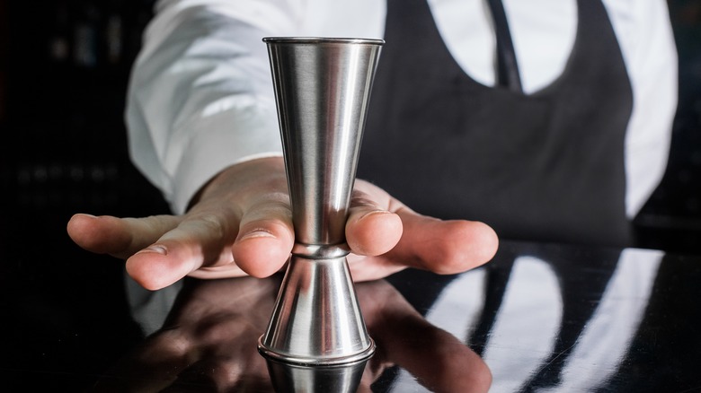 bartender holding jigger on bar