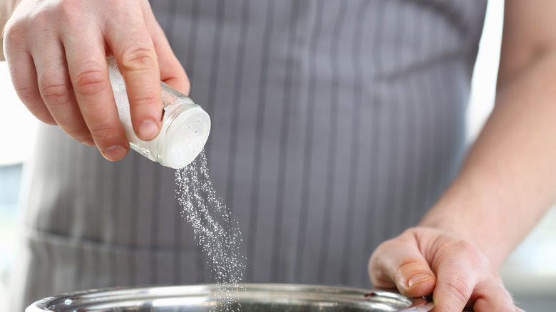 A man adding salt to a dish